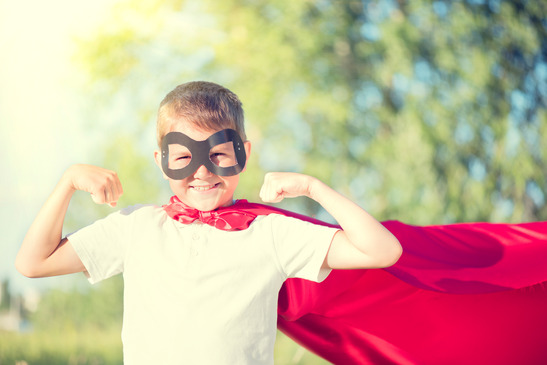 Little boy wearing superhero costume showing muscles