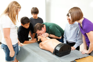 High school health class instructor demonstrates CPR lifesaving techniques for his students.