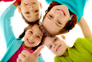 Photo of joyful children touching by their heads with girl her thumb up